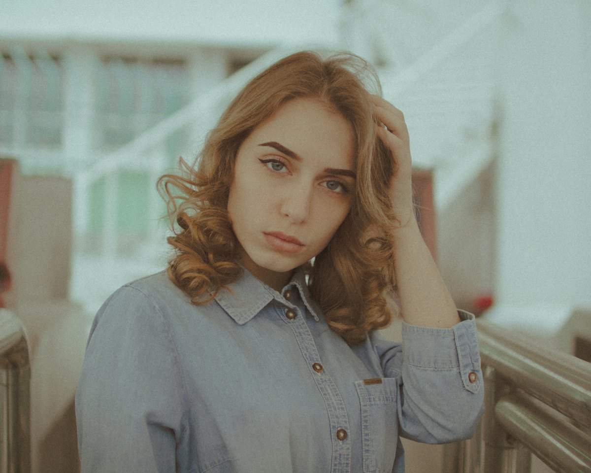 Женщина с тревожным взглядом касается головы рукой: внутреннее напряжение